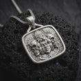 Load image into Gallery viewer, Polished sterling silver Aztec pendant displayed on dark volcanic stone, highlighting the jaguar headdress, skull motifs, detailed warrior face, feathers, and geometric Mexica-inspired ornament.