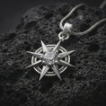 Load image into Gallery viewer, Polished sterling silver BG3 Gale charm displayed on dark volcanic stone, highlighting the sharp star points, circular frame, and sparkling faceted centerpiece.