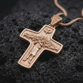 Load image into Gallery viewer, The rose gold plated Good Shepherd cross pendant is arranged on black volcanic rock, emphasizing the sculpted shepherd scene, sheep imagery, dove symbol, and meaningful Christian devotional design in a refined macro image.