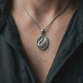 Load image into Gallery viewer, An oxidized sterling silver swan pendant is worn on the chest, displaying the graceful bird profile, layered wings, darkened recessed details, and flowing water-inspired ornamentation in a close-up lifestyle photograph.