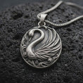 Load image into Gallery viewer, An oxidized sterling silver swan pendant rests on dark volcanic rock, featuring a graceful curved neck, layered feather wings, flowing water scrollwork, and dark recessed details in a premium macro close-up.