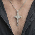 Load image into Gallery viewer, The polished silver Catholic crucifix is worn naturally on the chest, showing the sculpted Christ figure, Saint Benedict medal, structured cross silhouette, and detailed sterling silver finish.