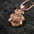 Load image into Gallery viewer, A rose gold plated gorilla samurai pendant displayed on textured volcanic rock, featuring an aggressive gorilla expression, ornamental helmet details, raised metal textures, and bold warrior-inspired design.
