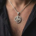 Load image into Gallery viewer, Polished silver Sicilian Triskelion pendant worn on the chest, featuring the traditional Trinacria symbol of Sicily with detailed Medusa relief and circular border.