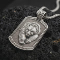 Load image into Gallery viewer, Polished sterling silver bear and cub necklace displayed on dark volcanic stone, highlighting the intertwined parent and cub portraits, realistic fur details, and rugged dog tag pendant.