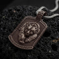 Load image into Gallery viewer, Bronze bear and cub pendant on black volcanic rock, featuring two sculpted bear faces, detailed fur, textured dog tag background, and decorative border.