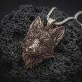 Load image into Gallery viewer, Bronze fox head pendant on black volcanic rock, featuring pointed ears, a narrow sculpted muzzle, expressive eyes, and detailed flowing fur.