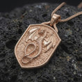 Load image into Gallery viewer, Rose gold plated dragon shield necklace displayed on textured volcanic stone, showcasing the winged dragon relief, serpentine body, detailed scales, and gothic fantasy styling.