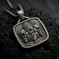 Load image into Gallery viewer, Oxidized sterling silver Aztec jaguar pendant on black volcanic rock, featuring a ceremonial human face, feline headdress, flanking skulls, feathers, and intricate Mesoamerican relief details.