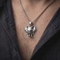 Load image into Gallery viewer, Polished silver elephant head necklace worn on the chest, featuring sculpted facial details, large ears, curved tusks, and a meaningful animal-inspired pendant profile.