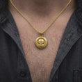 Load image into Gallery viewer, Gold plated Star Wars Mandalorian necklace worn on the chest, highlighting the iconic armored helmet, circular medallion border, and detailed sci-fi collectible jewelry design.