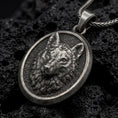 Load image into Gallery viewer, Oxidized sterling silver wolf head pendant on black volcanic rock, featuring a sculpted wolf face, detailed fur, pointed ears, textured background, and oval medallion frame.