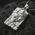 Load image into Gallery viewer, Polished sterling silver Gemini zodiac necklace displayed on dark volcanic stone, highlighting the twin face relief, flowing hair details, angular architectural borders, and dimensional silver design.