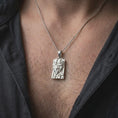 Load image into Gallery viewer, Polished silver Gemini pendant worn on the chest, featuring two closely connected faces, detailed hair textures, raised architectural elements, and a distinctive twin symbol design.