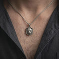 Load image into Gallery viewer, Oxidized sterling silver lioness pendant worn around the neck, showing the raised female lion portrait, strong facial structure, dark textured shield-shaped face, and braided silver necklace chain.