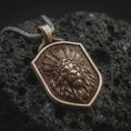 Load image into Gallery viewer, Bronze lion chief pendant necklace on black volcanic stone, featuring a majestic lion head wearing a detailed feather headdress, flowing mane, textured shield-shaped background, and braided silver chain.