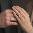 Load image into Gallery viewer, Rose gold matching Saint Benedict rings worn on the fingers of a man and woman together, highlighting circular Benedictine Cross medallions, sacred Latin inscriptions, intricate Celtic-inspired engravings, and matching rose gold finishes.