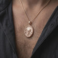 Load image into Gallery viewer, Rose gold plated Saint Pio of Pietrelcina pendant worn on the chest, showcasing the detailed saint portrait, traditional Capuchin habit, oval medallion frame, and Catholic religious jewelry aesthetic.