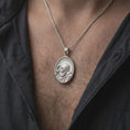 Load image into Gallery viewer, Polished silver Saint Padre Pio pendant worn on the chest, featuring the detailed Franciscan saint portrait, circular halo, traditional religious habit, and elegant oval Catholic medal.