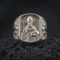 Load image into Gallery viewer, Polished 925 sterling silver St Nicholas Catholic ring resting on black volcanic stone, showcasing a sculpted bishop portrait with a circular halo, decorated mitre, curved pastoral staff, three balls on a book, and bright polished silver finish.