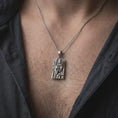 Load image into Gallery viewer, Oxidized sterling silver Gemini twins necklace worn on the chest, showing the two sculpted faces, dark recessed background, geometric rectangular border, and meaningful zodiac jewelry styling.