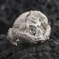Load image into Gallery viewer, Polished sterling silver Freemason skull ring displayed on dark volcanic stone, highlighting the three-dimensional skull face, deep eye sockets, detailed teeth, Masonic forehead symbol, and layered eagle feathers.