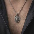 Load image into Gallery viewer, Oxidized sterling silver lion chief necklace worn around the neck, showing the raised lion portrait with a ceremonial-inspired feather headdress, dark textured shield face, flowing mane, and silver chain.
