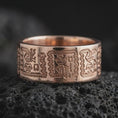 Load image into Gallery viewer, Rose gold plated 925 sterling silver Aztec Mayan band resting on black volcanic stone, highlighting intricate symbolic figures, angular geometric patterns, repeating ancient-inspired engravings, and a warm rose gold finish.