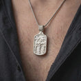 Load image into Gallery viewer, Polished Silver Calvary necklace hanging on a man's chest, highlighting the detailed three-cross biblical scene and rectangular medal.
