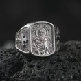 Load image into Gallery viewer, Polished Silver Saint Paul ring on black volcanic rock, highlighting the rectangular saint portrait, engraved inscription, and geometric background.
