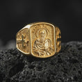 Load image into Gallery viewer, Gold Plated Saint Paul Apostle ring displayed on black volcanic rock, showcasing the raised side crosses and decorative diamond-patterned band.