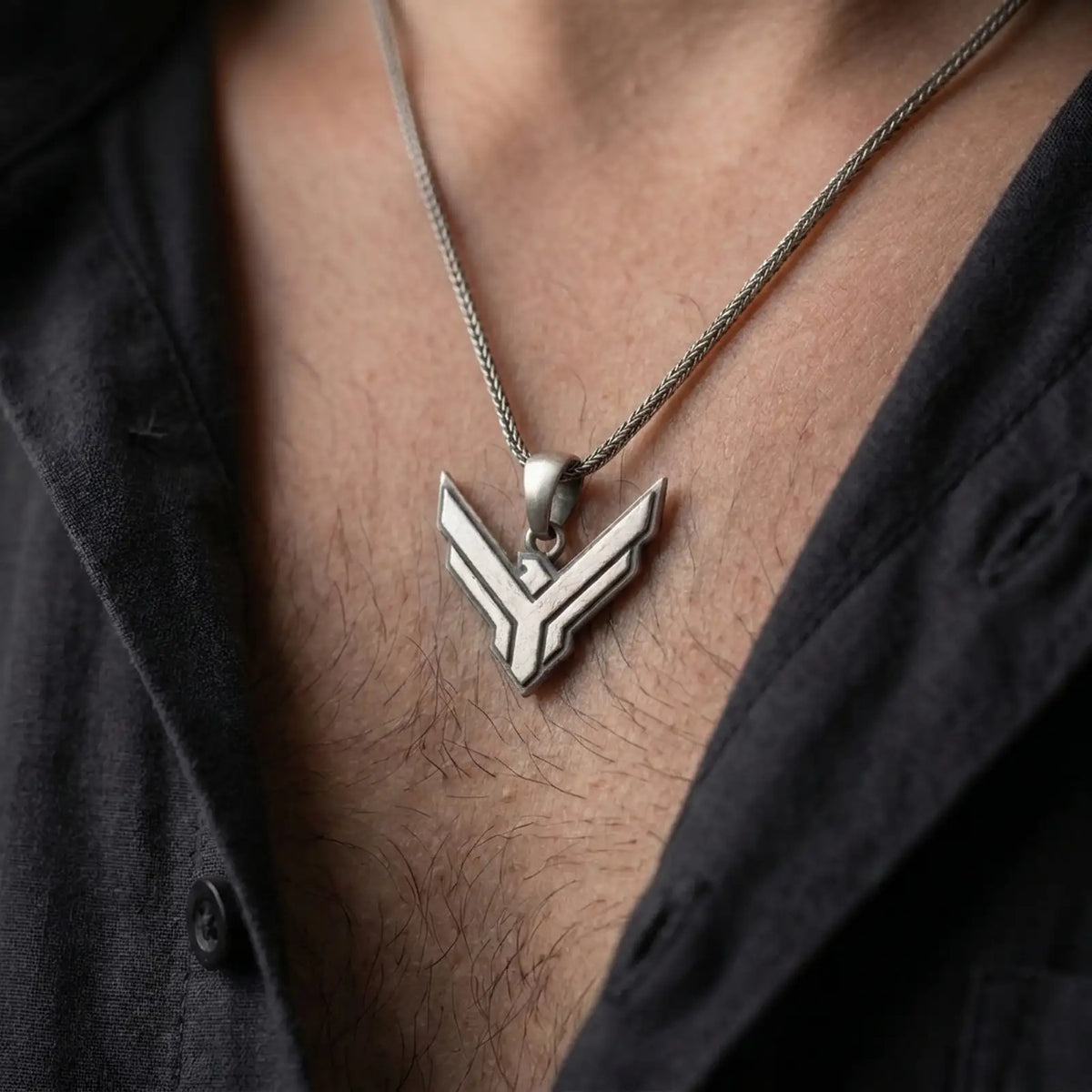 Oxidized sterling silver House Atreides necklace worn on the chest, showing the angular hawk emblem, dark recessed details, and bold Dune inspired pendant profile.