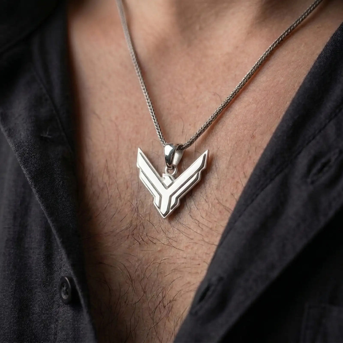 Polished silver House Atreides pendant worn on the chest, featuring the sharp geometric hawk symbol and clean futuristic styling inspired by the world of Dune.