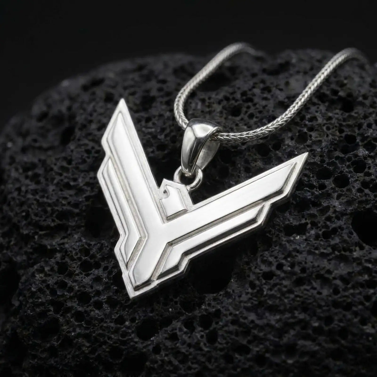 Polished sterling silver House Atreides necklace displayed on dark volcanic stone, highlighting the sharp hawk symbol, clean raised borders, and futuristic sci-fi styling.