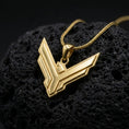 Load image into Gallery viewer, Gold plated House Atreides pendant resting on black volcanic rock, featuring the iconic hawk emblem, angular geometric lines, and bold Dune inspired necklace design.

