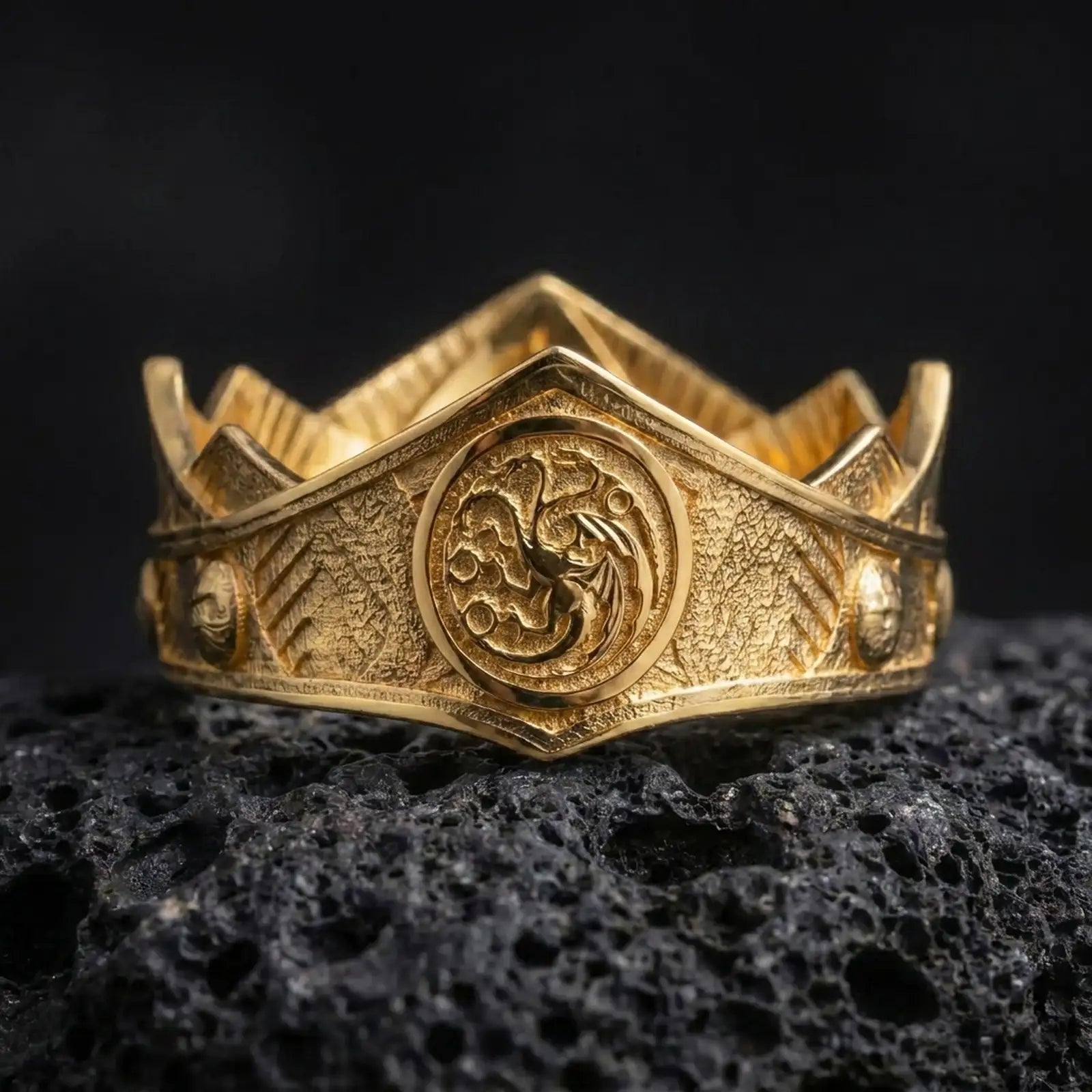 
Gold plated Targaryen dragon ring on textured volcanic rock, premium close-up studio composition emphasizing the dragon sigil, angular ring face, and medieval 