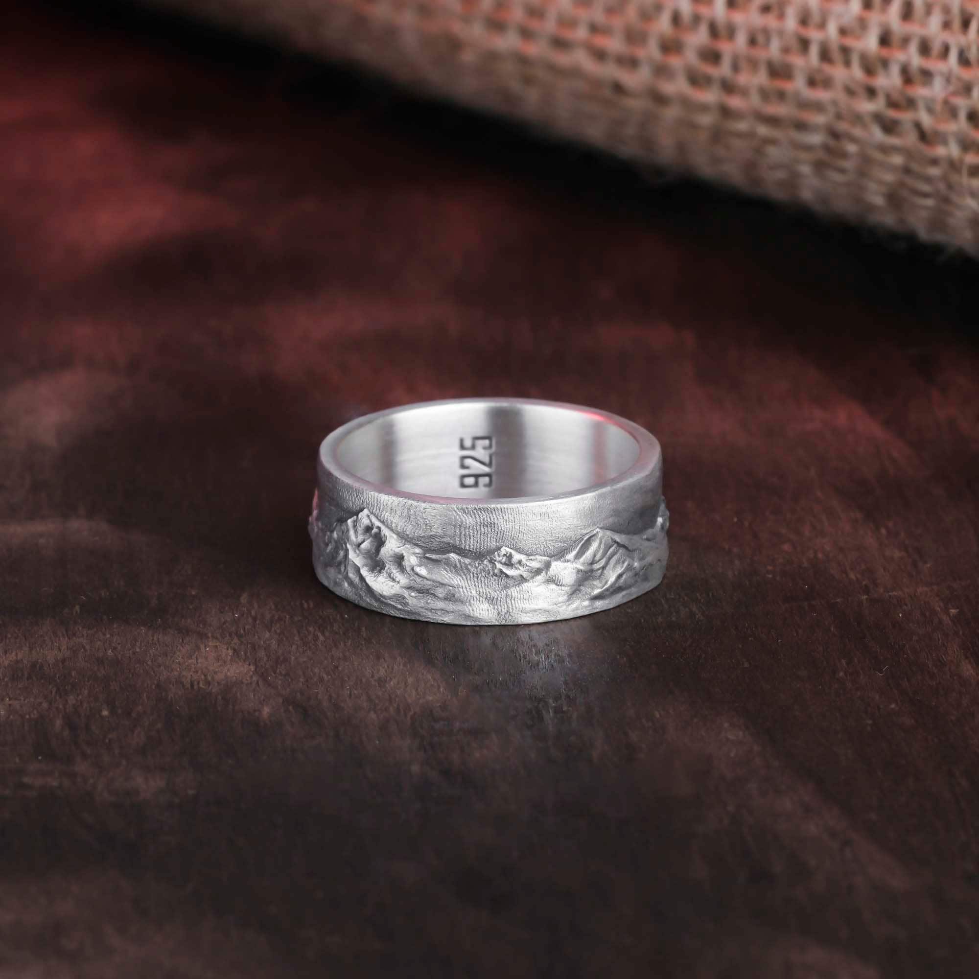 Close-up view of sterling silver ring engraved with a stunning mountain scene