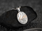 Silver swan pendant on woven chain, serene animal motif.
