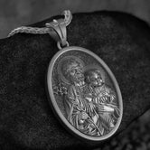 Oxidized silver oval pendant of Saint Joseph and Child Jesus with Sacred Heart symbols,