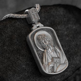 Oxidized rectangular Saint James pendant on black stone background,