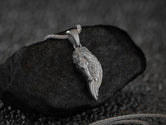 Oxidized silver pegasus wing horse necklace on dark stone background,