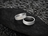 Two bright silver rings with structured grid design for couples