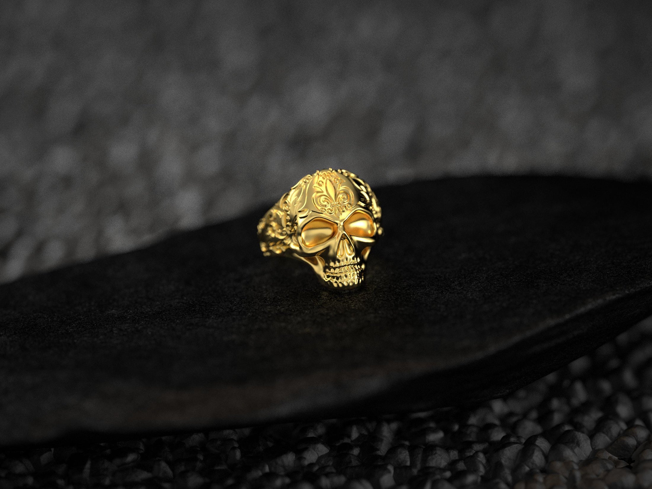 Front view of gold-plated skull ring with fleur-de-lis detail.