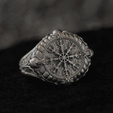 Front close-up of sterling silver Vegvísir signet ring on black stone.