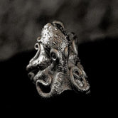 Close-up of sterling silver octopus signet ring on black stone.