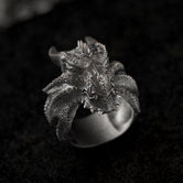 Close-up of the sterling silver Dragon Wyrm Scales ring perched on a smooth black stone.