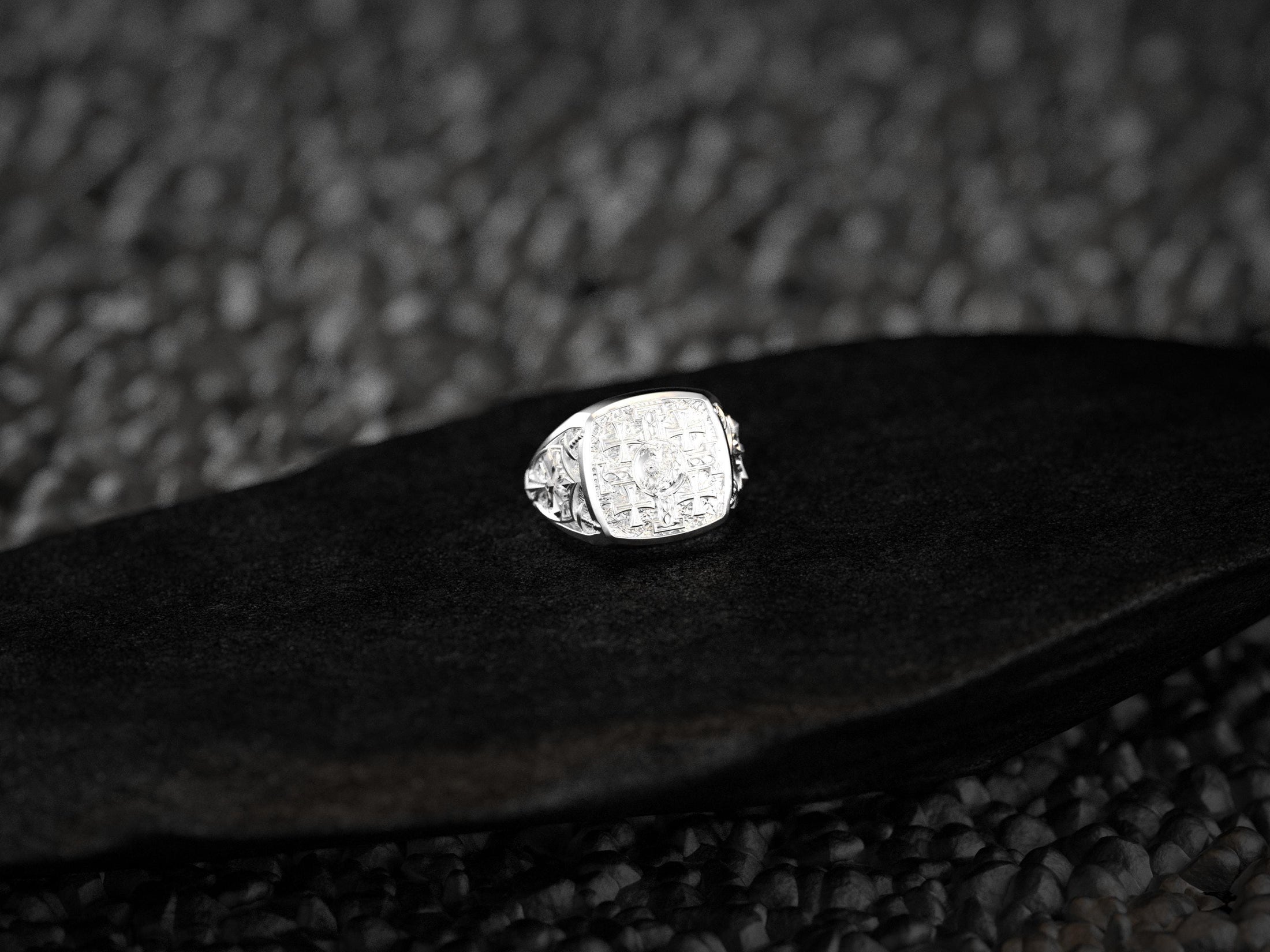 Front-view of the polished sterling silver signet ring engraved with the five-cross Jerusalem motif, set on black stone.