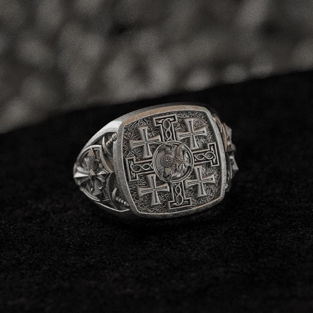 Front-view of the oxidized silver signet ring engraved with the five-cross Jerusalem motif, set on black stone.