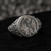 Close-up front view of the polished sterling silver ring face featuring the Good Shepherd cradling a lamb, on black stone.