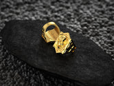 Angled shot of the gold-plated ring, displaying its polished edges and contrasting matte brickwork.